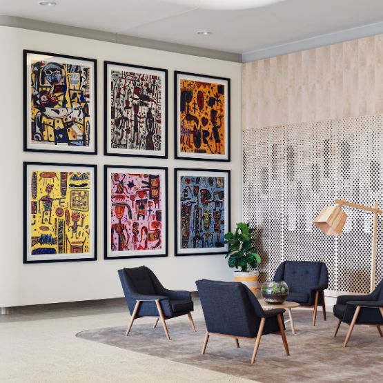 A hotel room with an orange patterned bed and an abstract painting